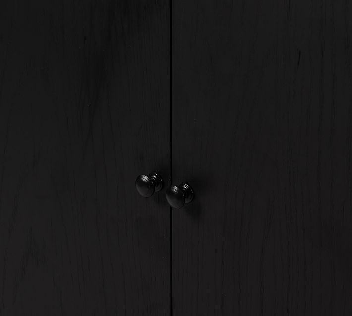 Close-up of black cabinet doors with round knob handles.