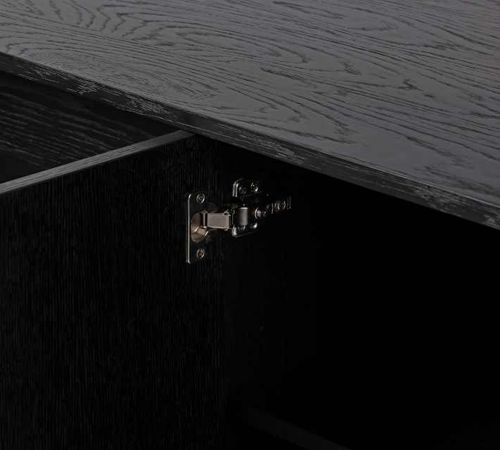 Open drawer inside a black wood cabinet showing the interior and metal hinge.