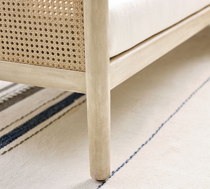 Leg of the sofa with woven cane panel along the bottom edge