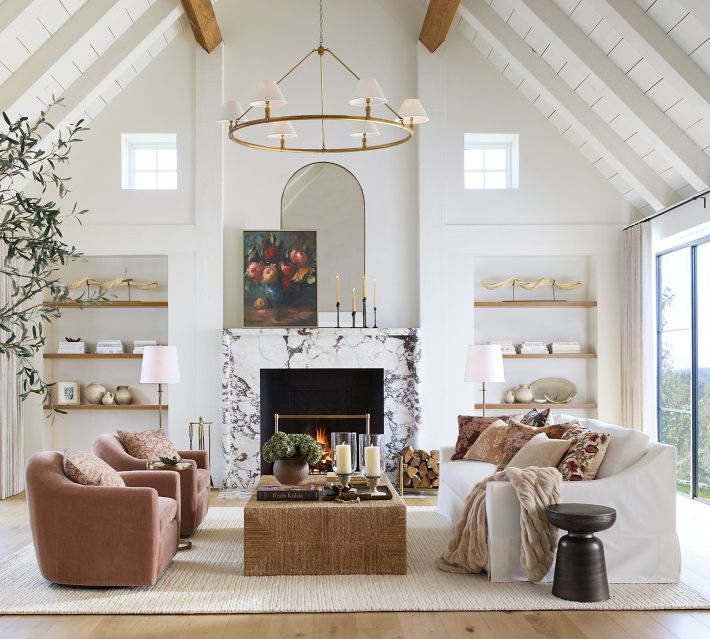 Bright contemporary living room with white sofas, marble fireplace, and gallery wall.