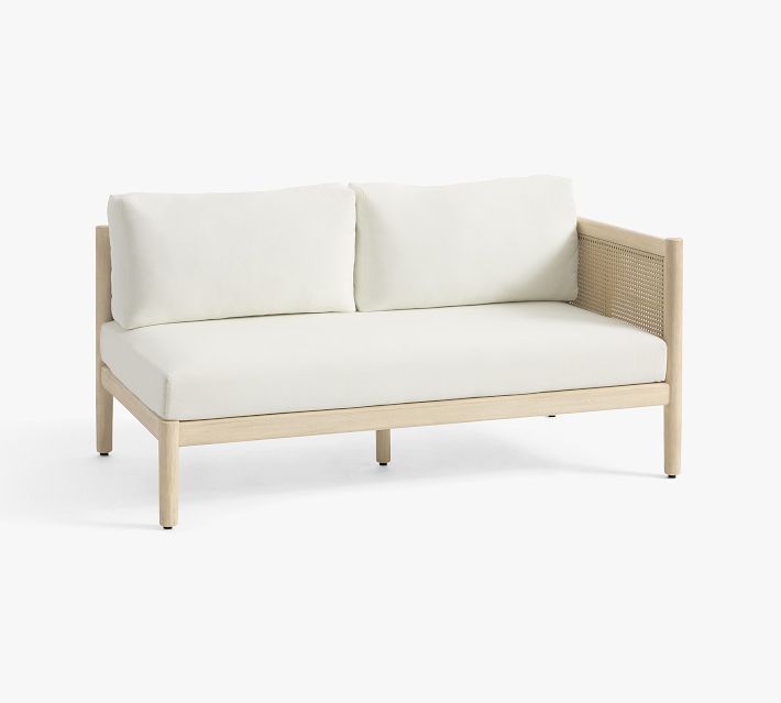 Three-quarter view of white cushioned sofa with cane side panels