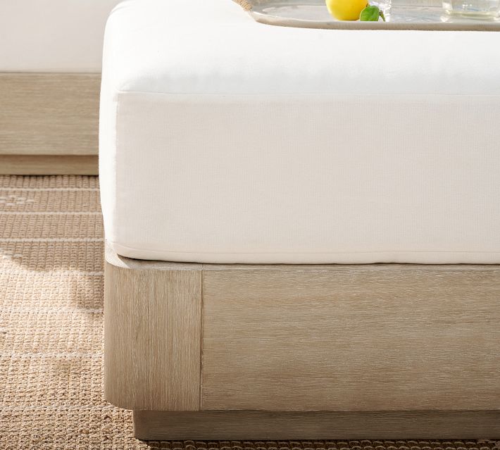 Close-up of white cushion on a wooden ottoman base