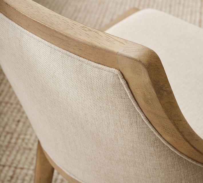 Close-up of the chair armrest and upper back showing wooden arm support and beige fabric