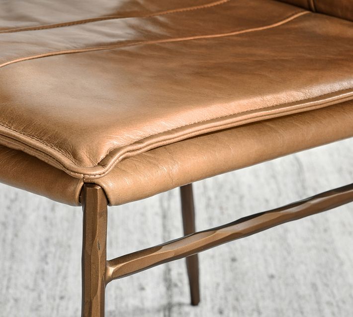 Close-up of tan leather upholstery and wooden frame edge