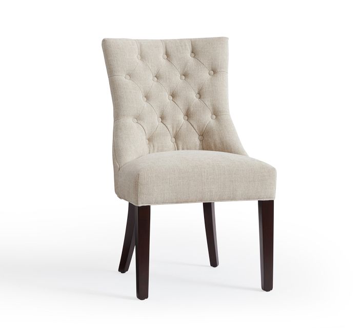 Beige upholstered dining chair with tufted back and dark wooden legs, side view