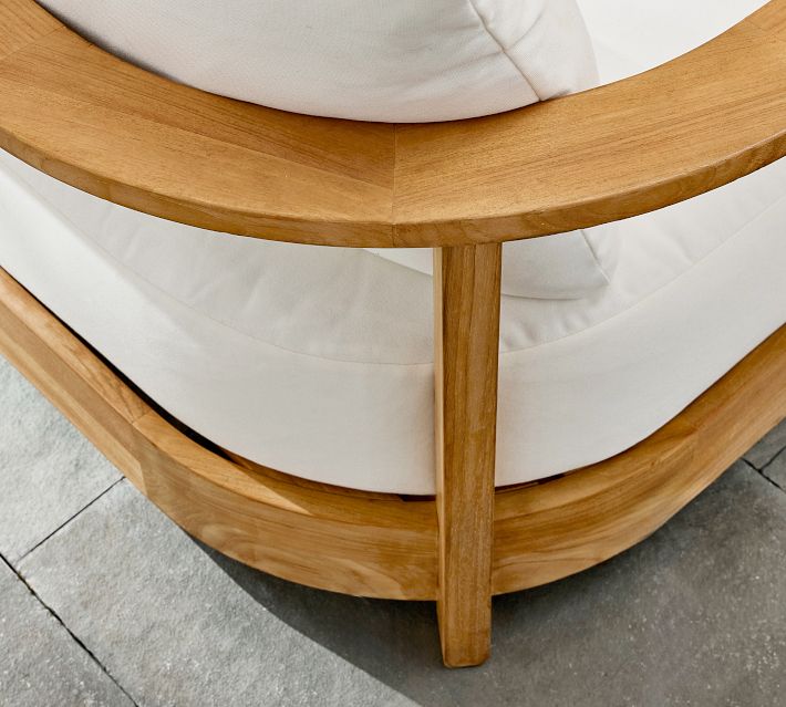 Close-up of curved wooden armrest and white couch cushion