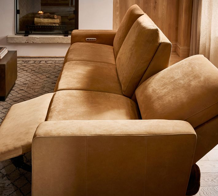 Chair-height view of tan leather sofa showing recliner extended and cushions.