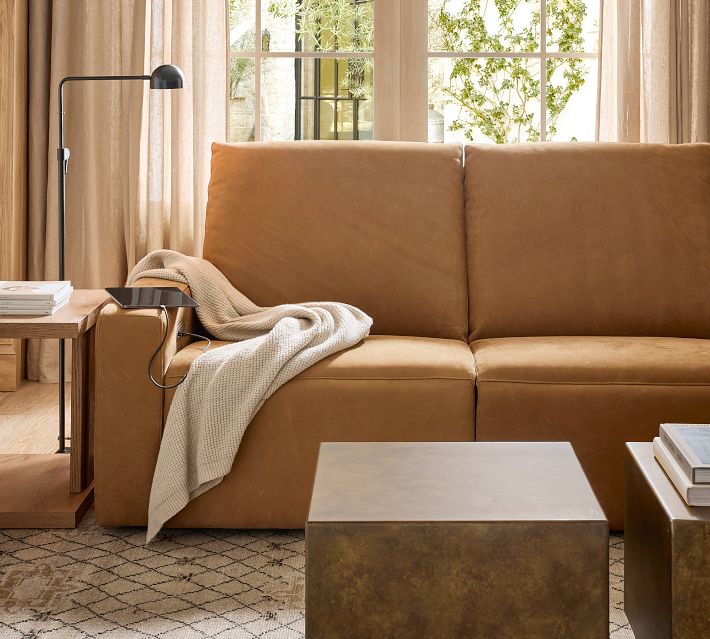 Tan leather sofa with built-in charging port on the armrest and floor lamp nearby.