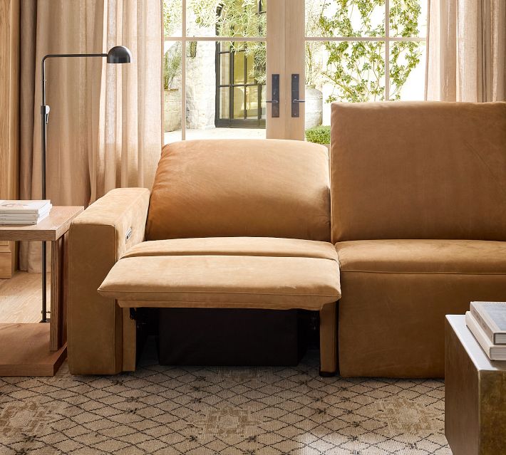 Close-up of tan leather sofa armrest with charging cable nearby.
