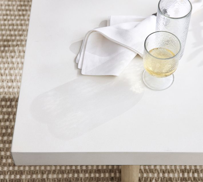 White table edge with a folded napkin and a glass of white wine.