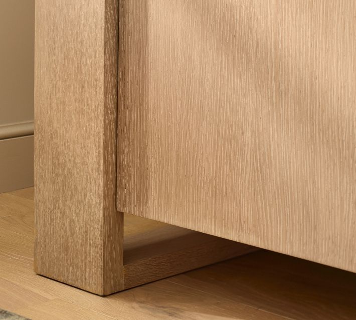 Close-up of the bottom leg of the cabinet showing wood grain and open shelf space