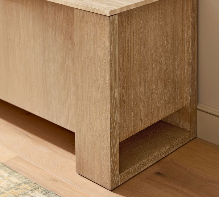 Corner view of the wooden cabinet showing lower leg and open shelf area