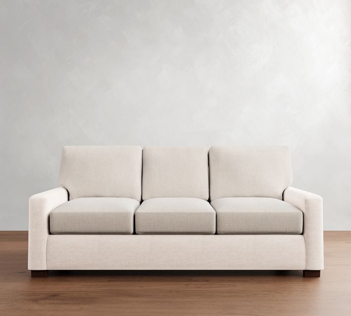 A three-seat light beige sofa with three back cushions.