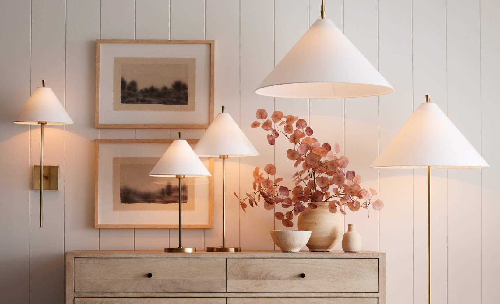 Minimalist lighting setup featuring various white lamps with brass accents, including table lamps, wall sconces, and a pendant light.