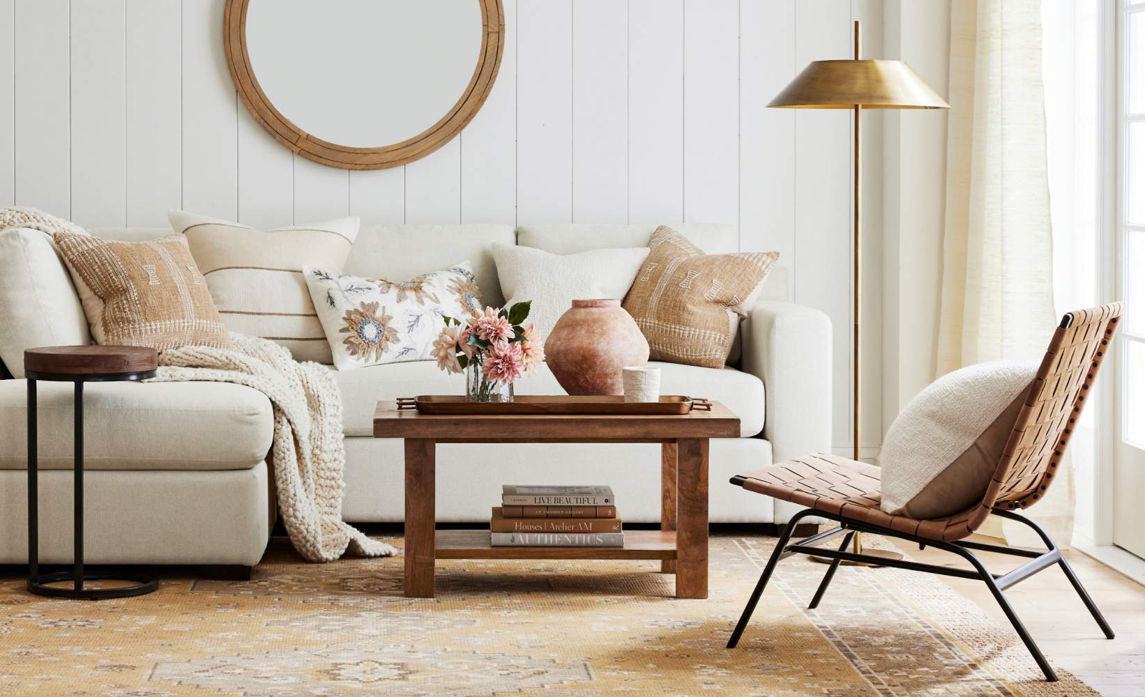 Cozy, modern living room featuring a light beige sofa with textured pillows and a knitted throw.
