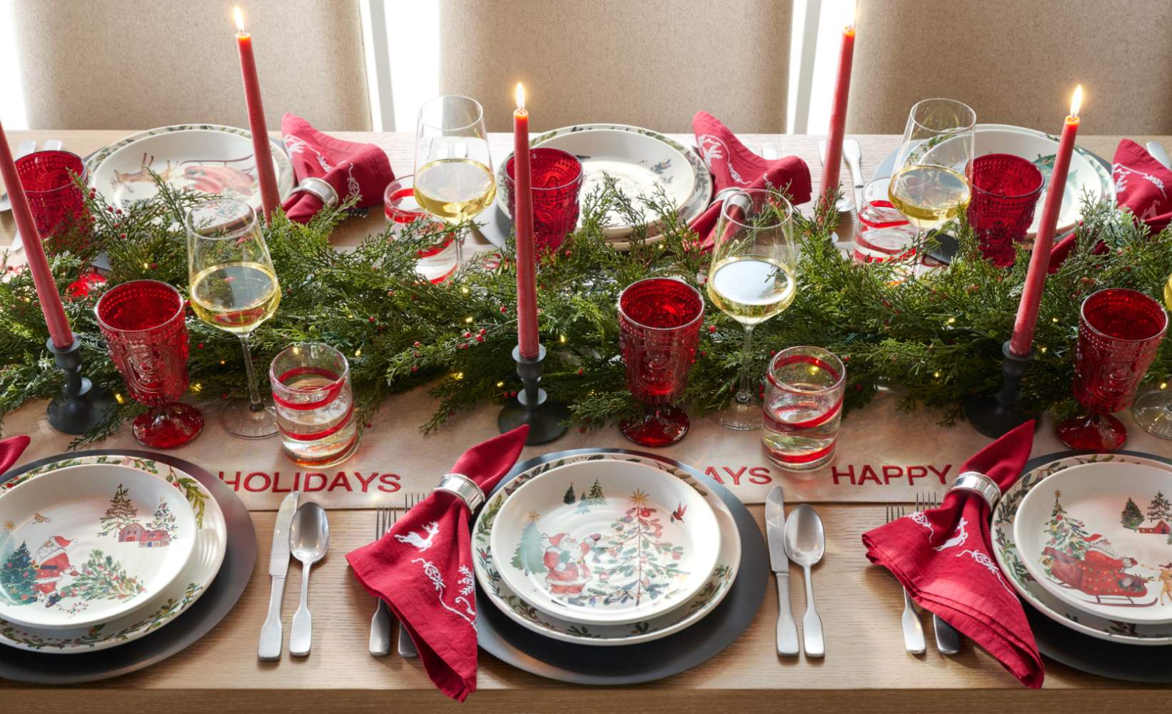 Christmas table centerpiece featuring pillar candles, greenery, and festive holiday decor.