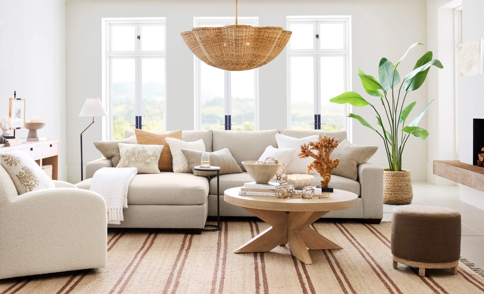 Modern neutral-toned living room with a beige sectional sofa, large indoor plant, wooden round coffee table, and natural woven chandelier. Modern neutral-toned living room with a beige sectional sofa, large indoor plant, wooden round coffee table, and natural woven chandelier.