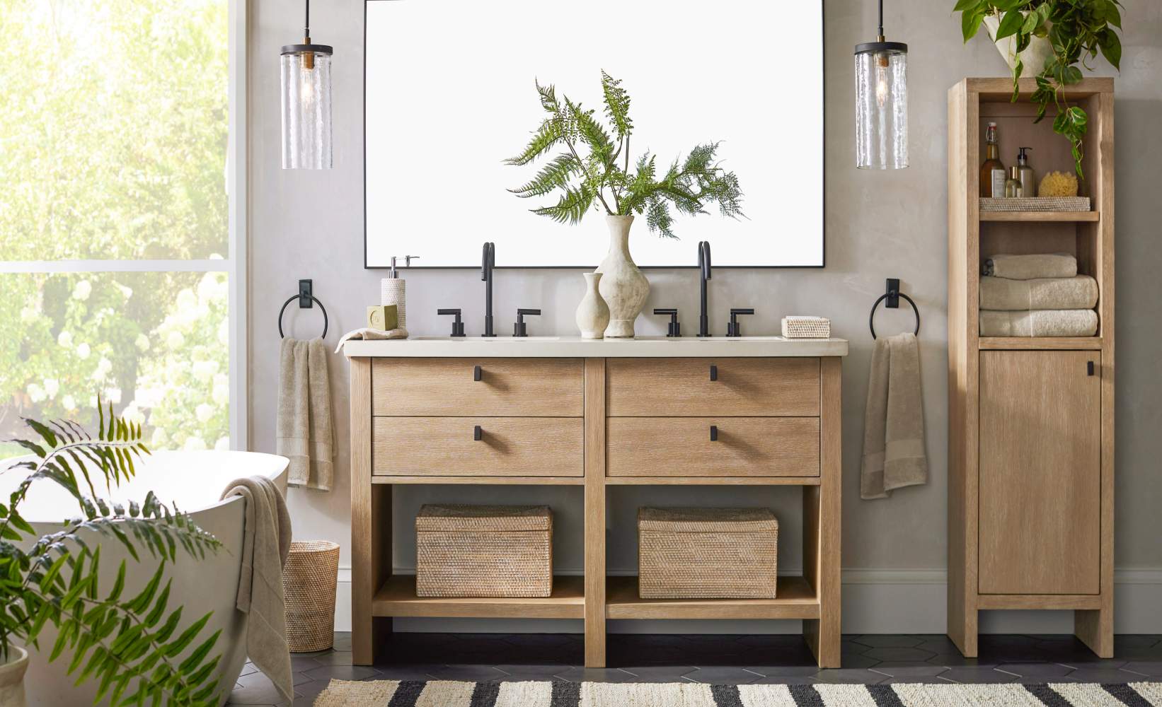 Modern farmhouse bathroom featuring double vanity in light oak with white countertop, matching bath linen tower storage cabinet, and striped bathroom rug