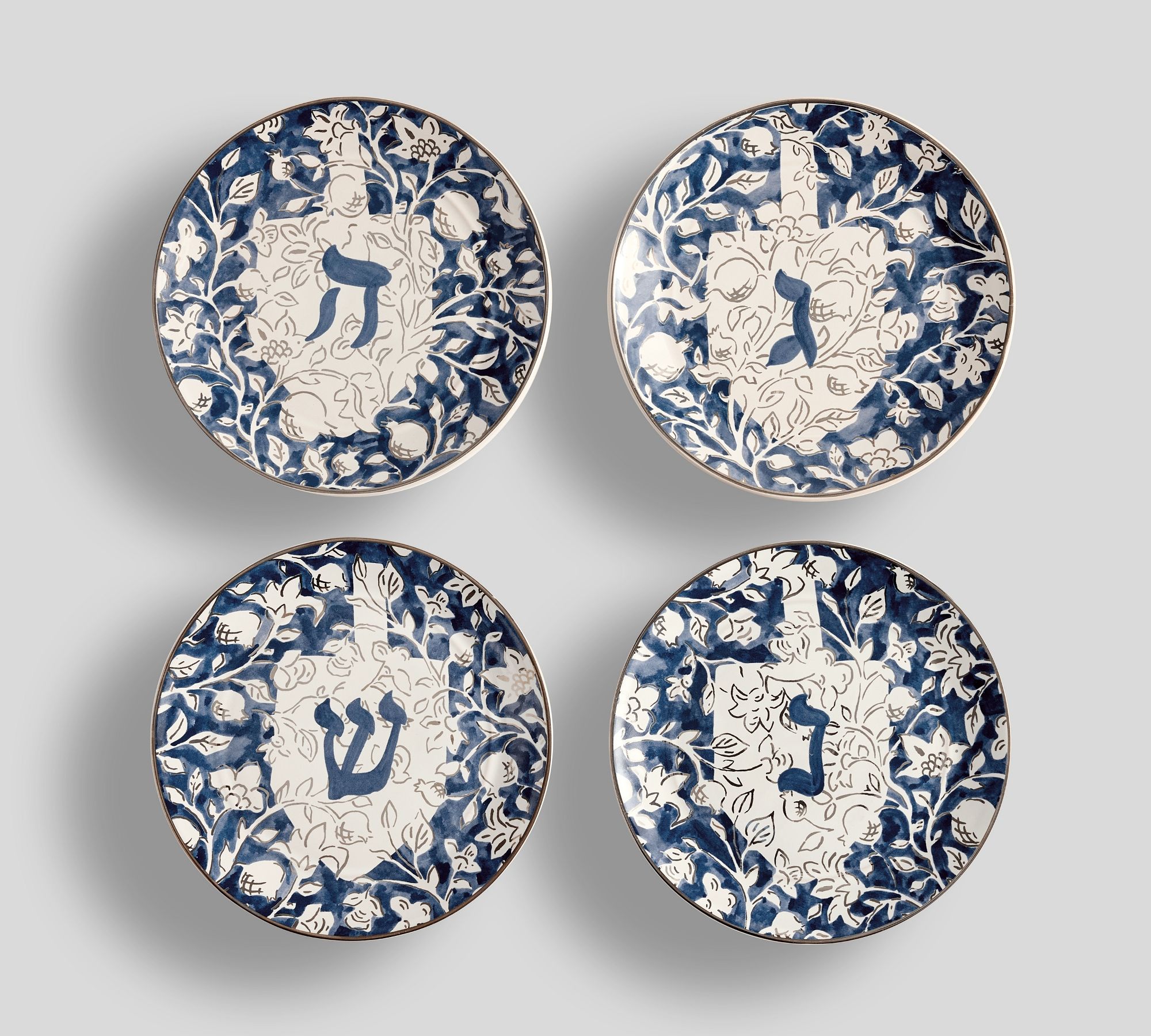 Four blue and white floral plates with dreidels on them