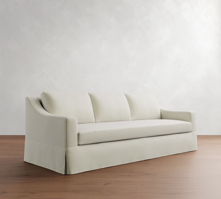 A white upholstered sofa with rounded arms and three seat cushions in a living room setting.