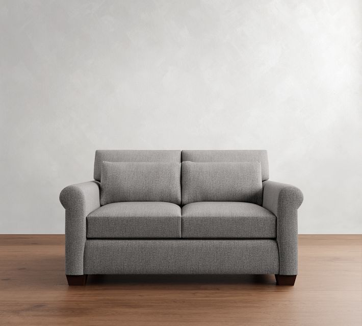 Gray fabric sofa centered in a room with wooden floor and light gray wall.