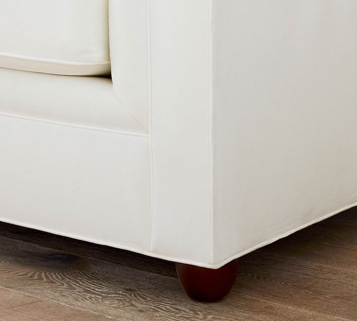 Lower corner of white sofa showing wooden leg and fabric edge