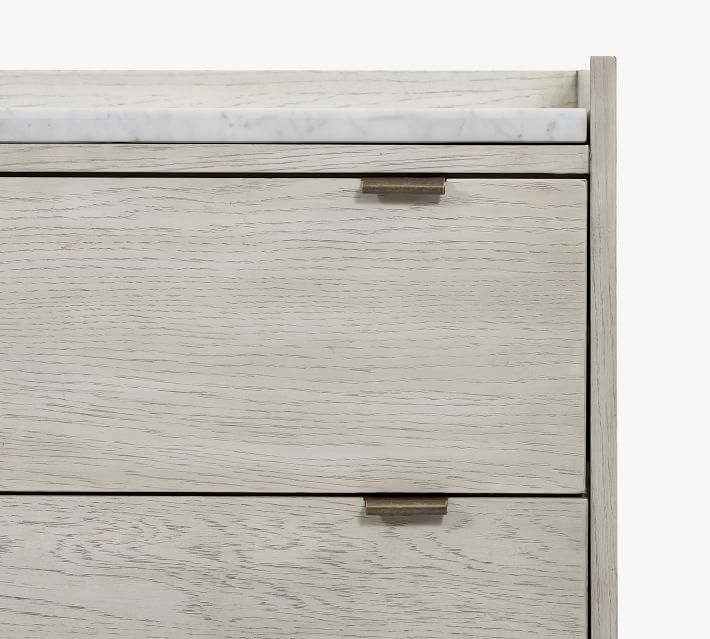Top drawer with small brass handle on a light wood dresser