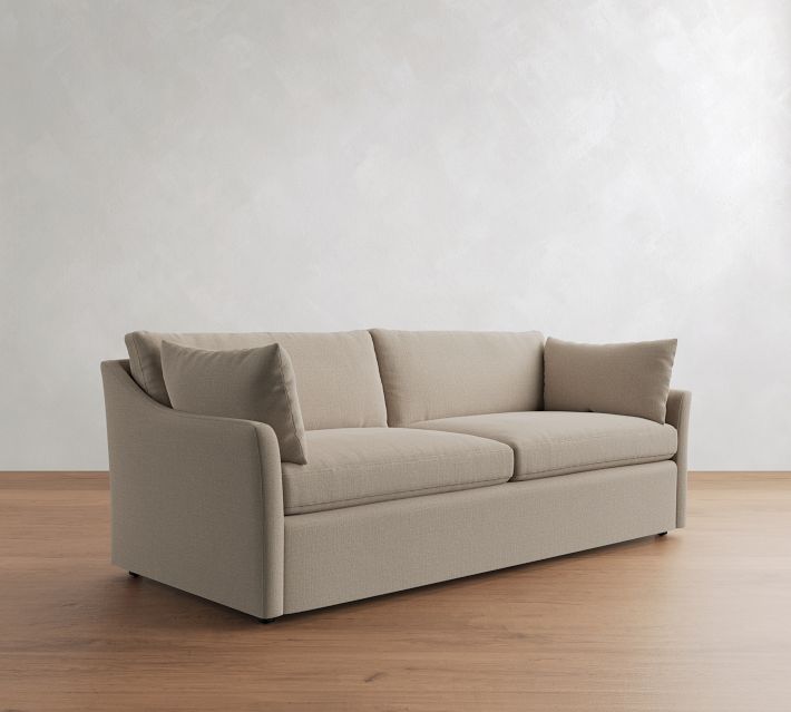 Three-quarter view of beige sofa with cushions from left side.