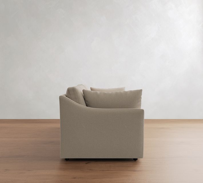 Side view of beige fabric sofa showing one armrest and back cushions, on wooden floor.