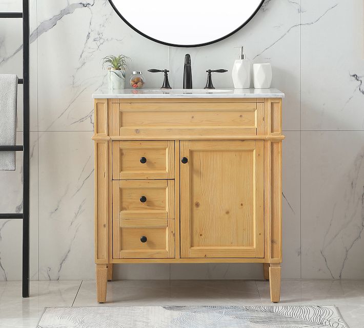 Wood vanity with marble top in a bathroom with round mirror and towel rack
