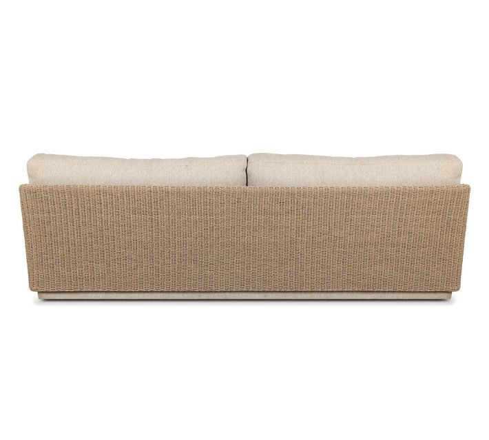 Rear-side view of beige fabric sofa showing woven rattan back panel