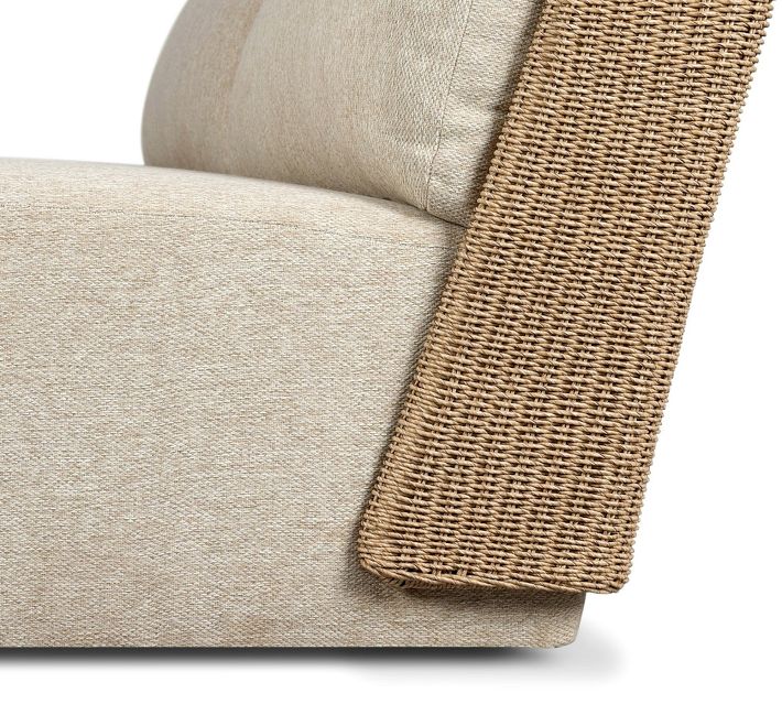 Corner view of woven rattan armrest with beige upholstery on outdoor sofa