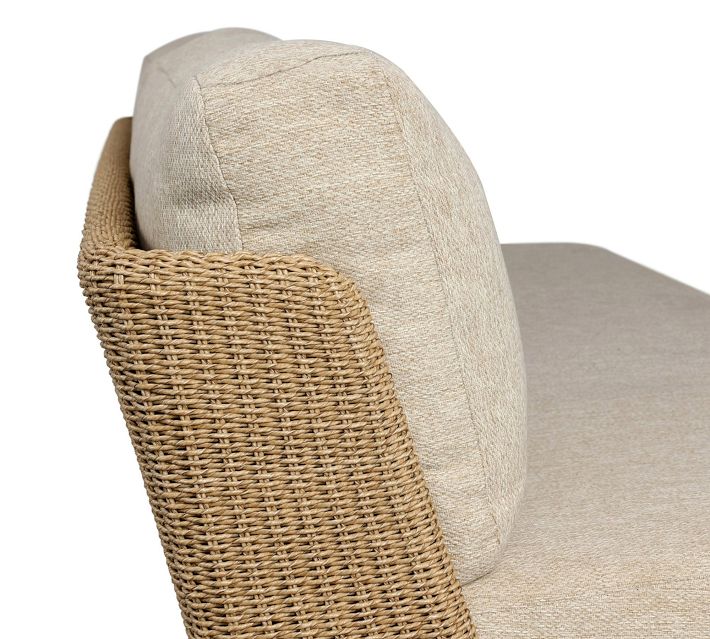 Close-up of woven rattan armrest on beige fabric outdoor sofa