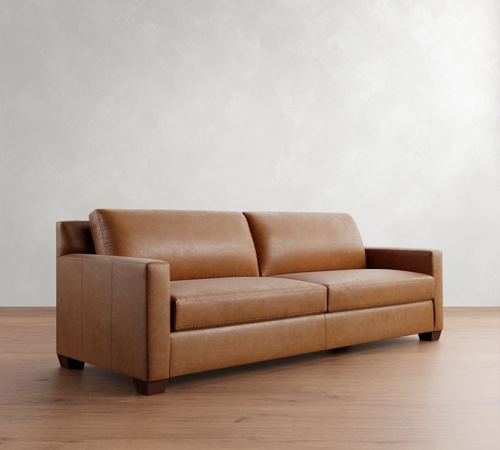 A brown leather sofa shown in a three-quarter view with large armrests and two-seat cushions.