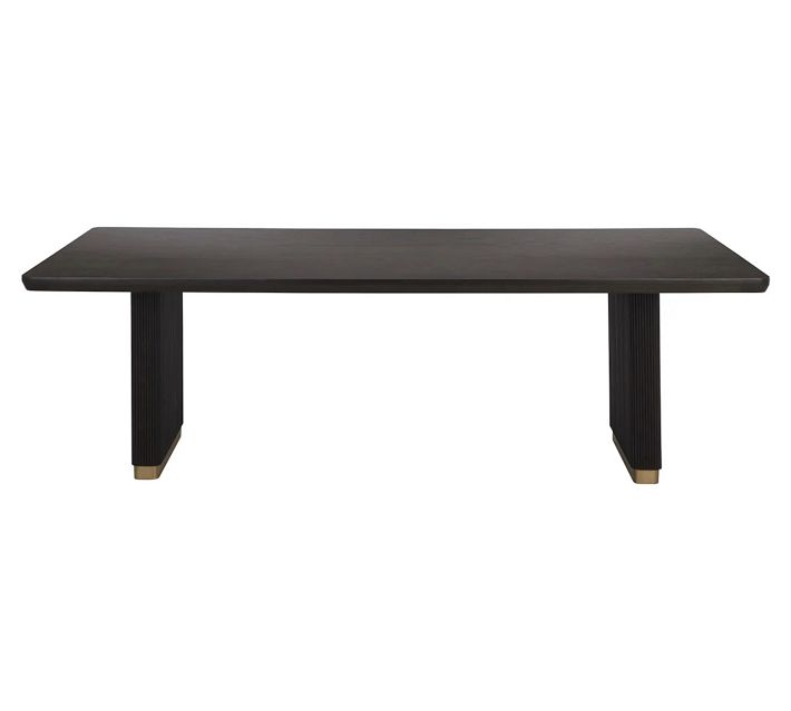Dark wood dining table with ribbed pedestal legs and brass base feet.