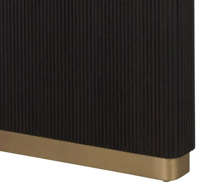 Close-up of ribbed dark wood table leg with brass base trim.