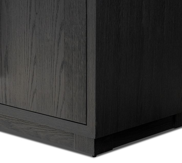 Close-up of the lower corner of a dark wood cabinet with base trim