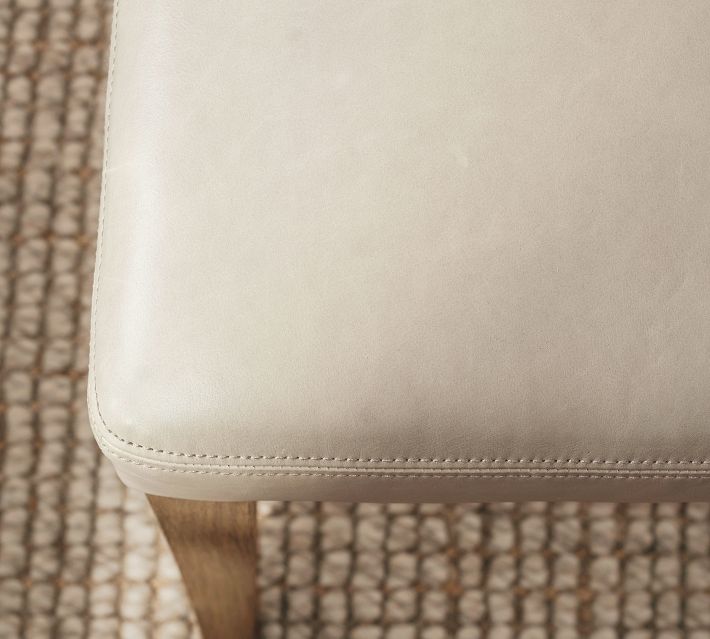 Beige upholstered chair seat edge showing stitching