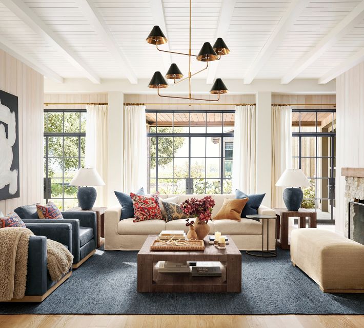 Bright living room with beige sofas, dark blue chairs, coffee table, and decorative pillows.