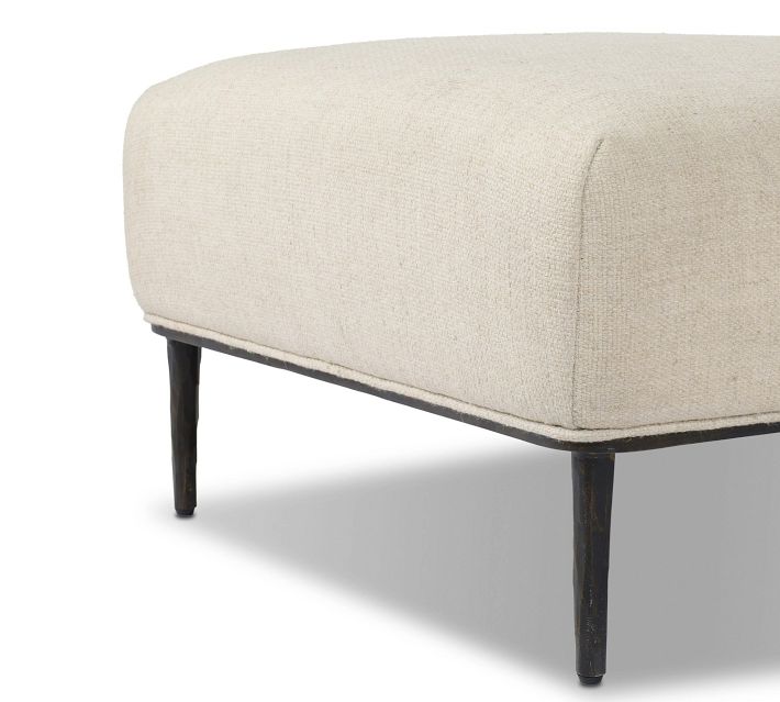 Draft of low-angle shot showing bottom edge and legs of beige ottoman