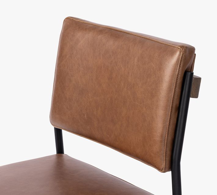 Close-up of the brown leather backrest on a black metal chair frame showing stitching and leather texture.