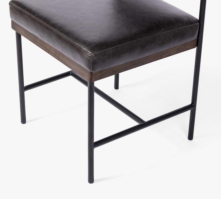 Close-up of black leather seat and wooden trim along seat edge.