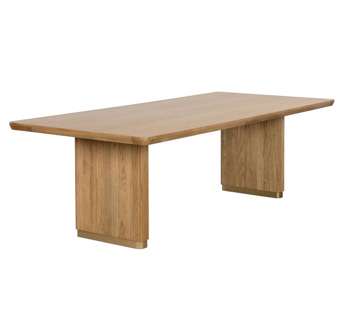 Close-up of light wood dining table showing rounded edge and thick pedestal leg.