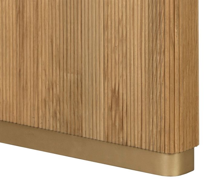 Close-up of ribbed wood table leg with brass-toned base.