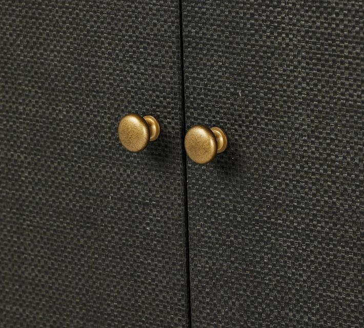 Brass/gold round cabinet knobs on dark textured cabinet doors.