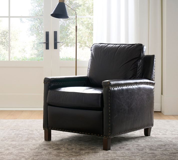 Single black leather armchair facing camera with window background.