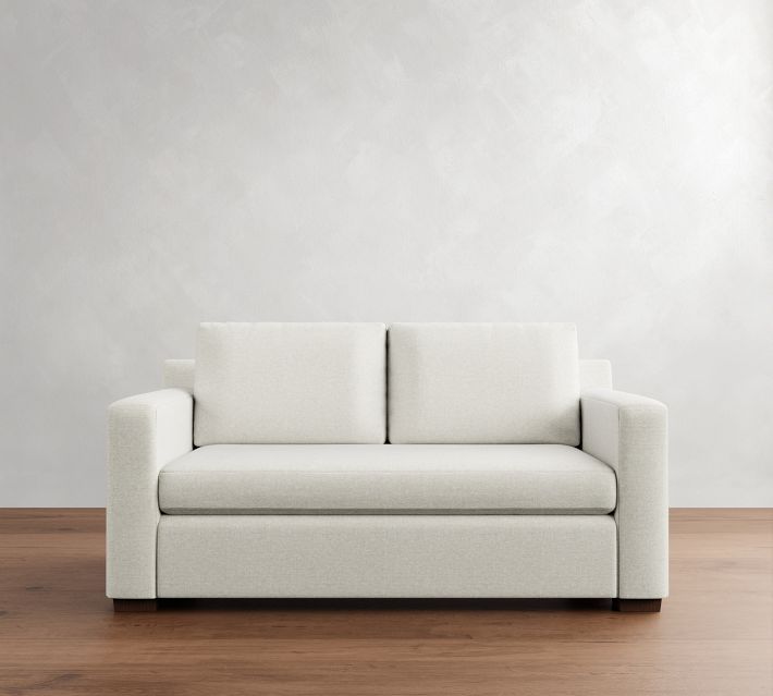 Two-person sofa in light beige fabric against textured wall