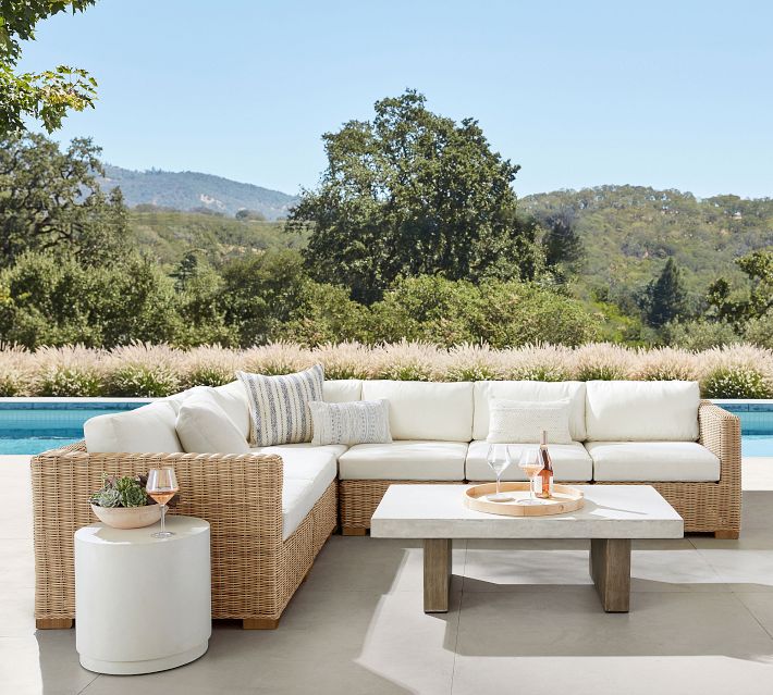 Poolside outdoor seating area with sectional and view of distant hills.