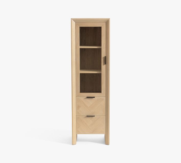 Full-length view of a tall freestanding wooden cabinet with glass door, three drawers at bottom, and chevron wood paneling.