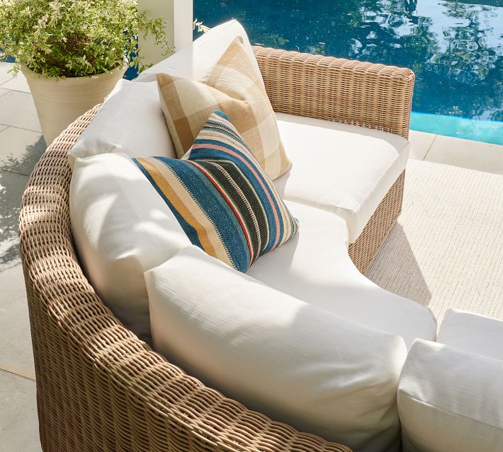 Rattan lounge chair with white cushions by poolside.